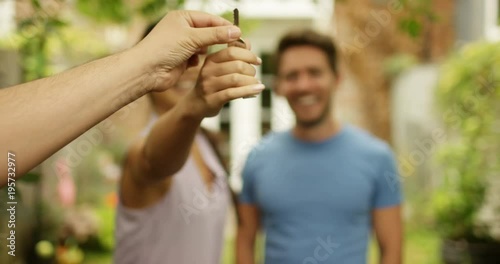 4K Happy couple in front of new home, taking the key from real estate agent. Slow motion. photo