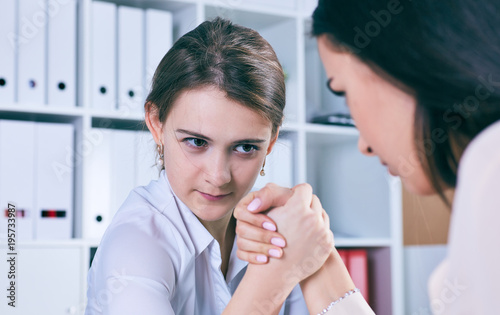Two female office wokers armwrestling, exerting pressure on each other, struggling for leadership.