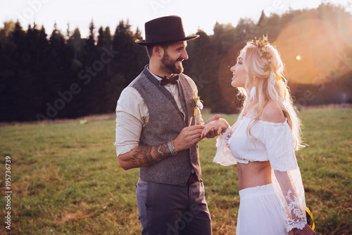 Lovely young couple in wedding dresses in Bohho style, on a field with a balloon photo