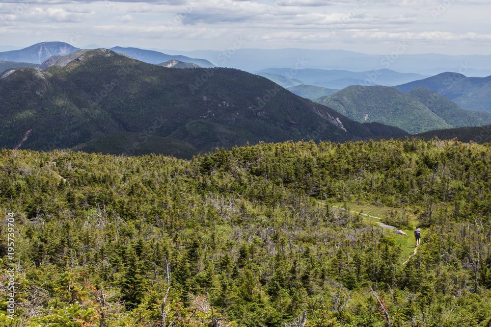 Hiker walking on beautiful mountain path with sweeping views into the Adirondack high peaks in New York