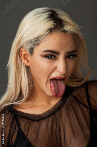 Blonde woman portrait wearing black tulle shirt with tongue stuck out