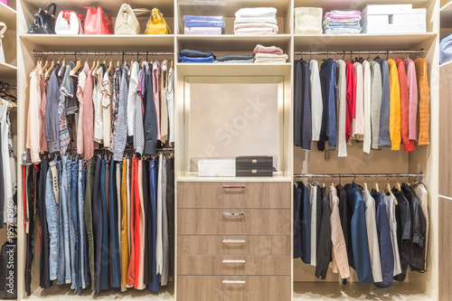 Modern wooden wardrobe with clothes hanging on rail in walk in closet design interior photo