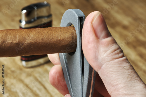 Photography A Cuban cigar with a male hand holding a cutter and a blurred lighter