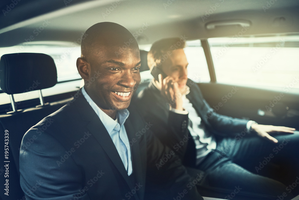 Smiling African businessman driving with a colleague to work