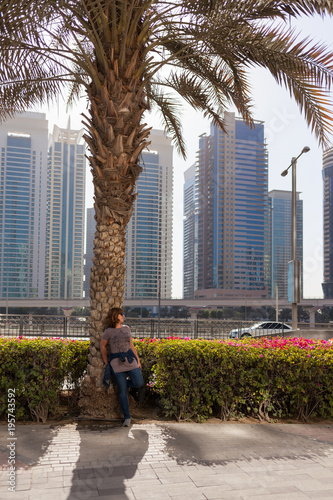 Woman next to palm tree across Jumeirah Lake Towers in Dubai