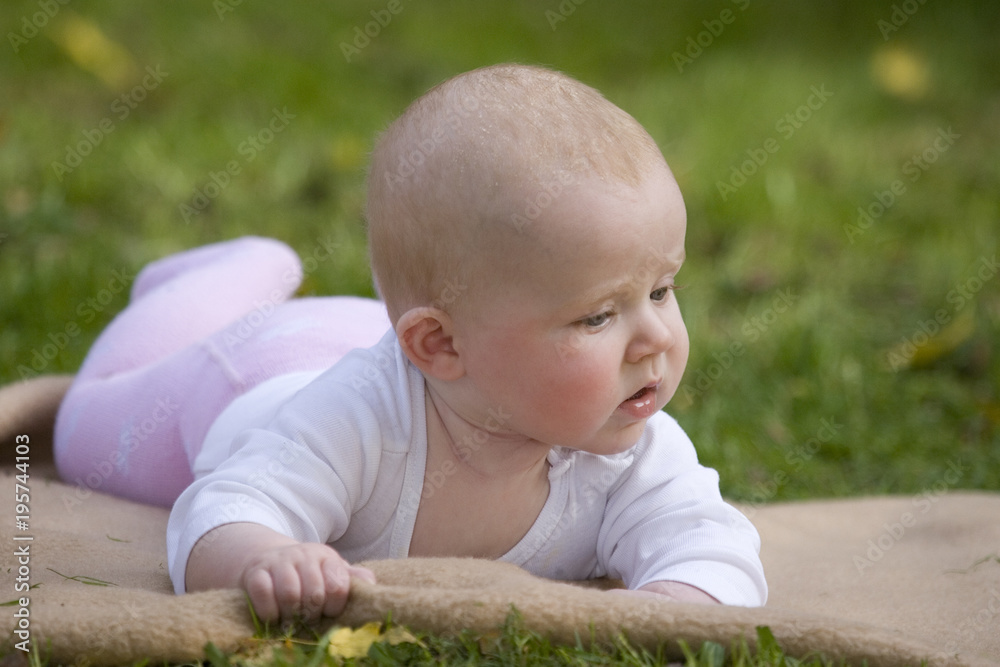 Kleines Baby liegt auf dem Rasen im Garten Kleines Baby liegt auf dem Rasen im Garten