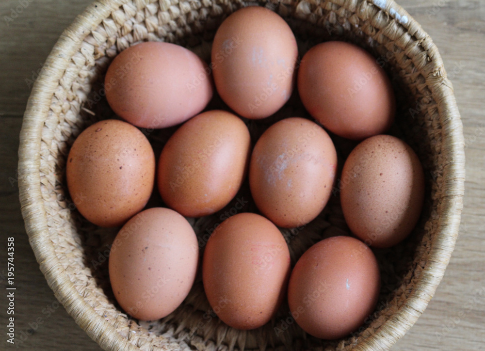 Brown chicken eggs in straw basket on wooden background in kitchen Brown chicken eggs in straw basket on wooden background in kitchen