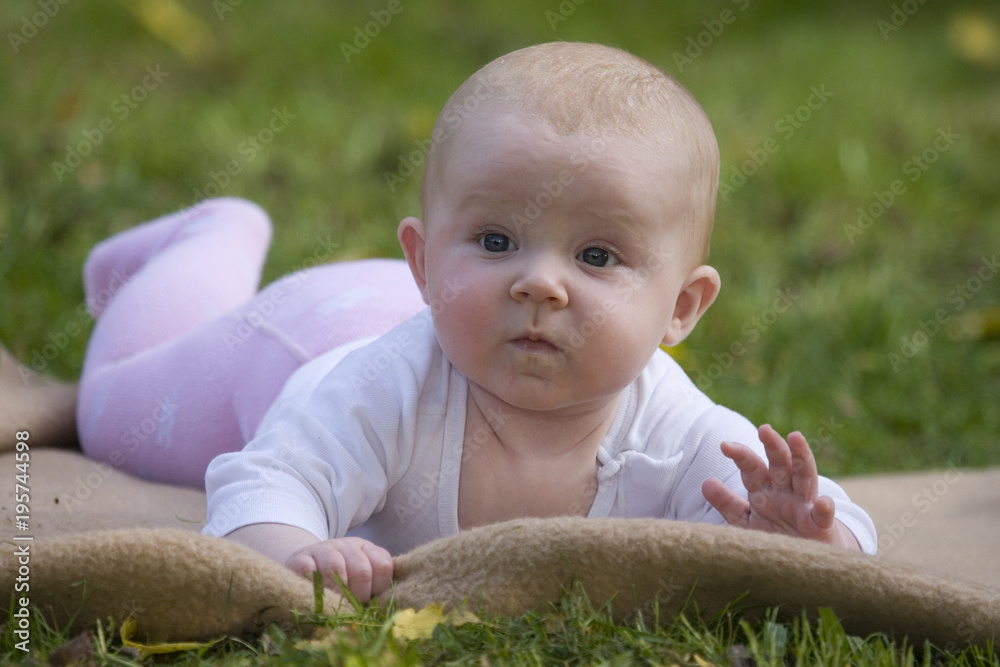 s-es-baby-liegt-auf-dem-bauch-auf-dem-rasen-im-garten-stock-photo