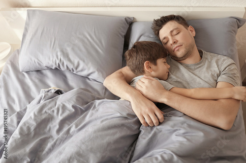 Father with son sleeping in bed at home