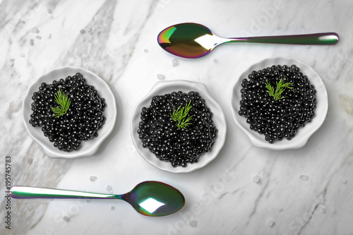 Plates with delicious black caviar on light background