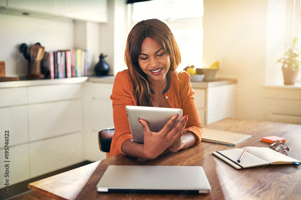 Smiling young woman working from home with a digital tablet Smiling young woman working from home with a digital tablet