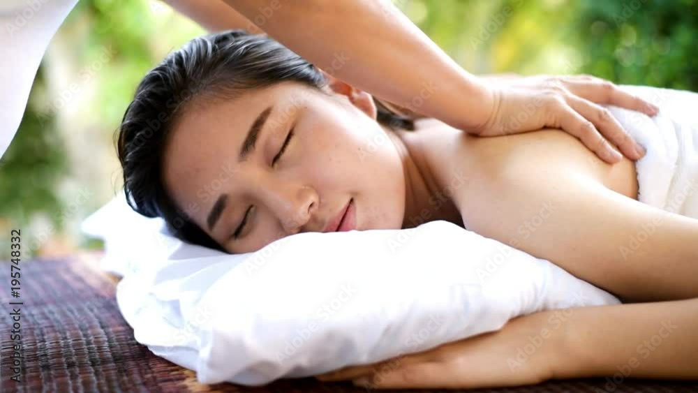 Slow motion of happy young Asian Thai woman relax on a bed and get massage at spa resort in a garden. Slow motion of happy young Asian Thai woman relax on a bed and get massage at spa resort in a garden.
