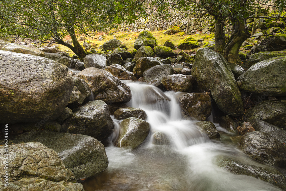 view of a stream flowing down from stickle tarn in langdale in the lake district national park in the north of england showing the blurred water moving down over dark rock view of a stream flowing down from stickle tarn in langdale in the lake district national park in the north of england showing the blurred water moving down over dark rock