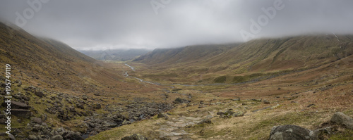 a view of the fells and crags in langdale in the lake district national park in the cumbria area of north england showing clouds and fog and the path leading away