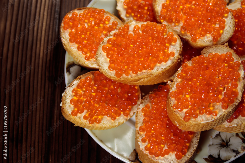 Sandwiches with butter and red caviar on wooden table Sandwiches with butter and red caviar on wooden table