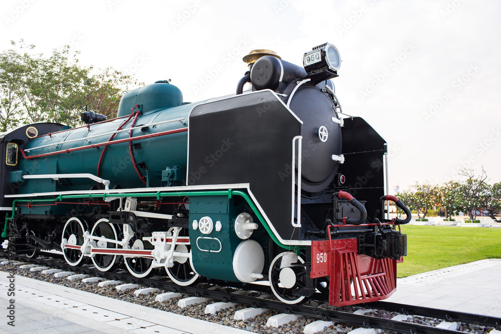Fototapeta premium An old steam locomotive in black and green color is shown in the park for people to take a look.