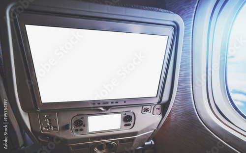 Empty white mockups of aircraft multimedia screens with remote control, close-up view of blank template of airplane monitor in passenger seat: many buttons and sockets, wide-angle shot