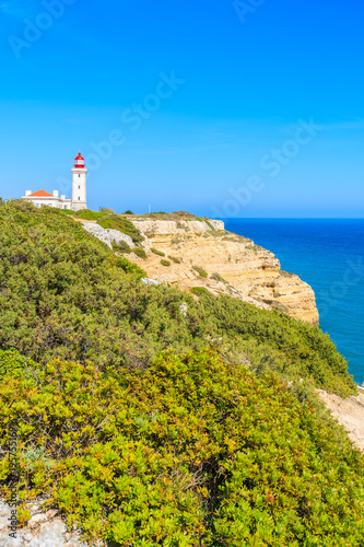 Lighthouse building on high cliff with sea in background near Carvoeiro town, Algarve, Portugal