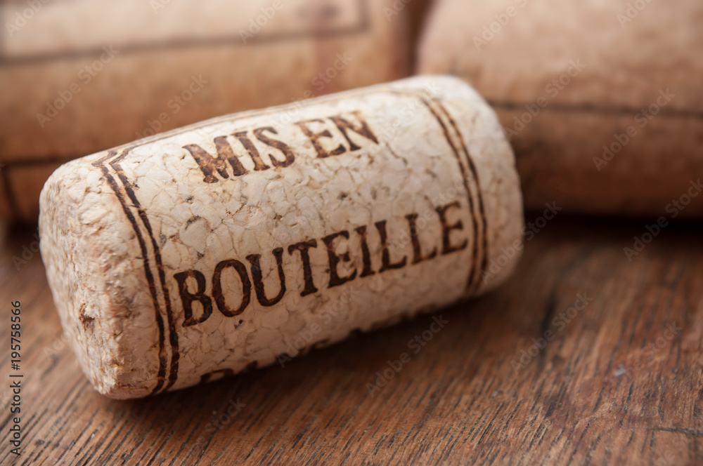 closeup of cork wine stopper with text - bottled on wooden table background  (traduction text in french - mis en bouteille)
