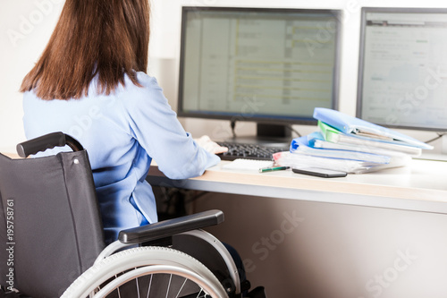 Foto Invalid or disabled woman sitting wheelchair working office desk computer