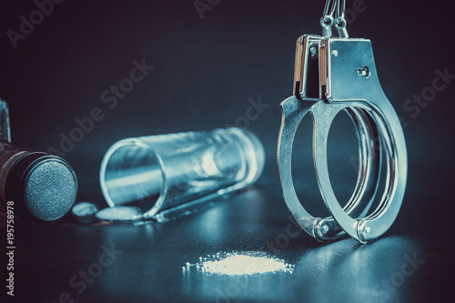 arrest of criminal. Handcuffs, alcohol whiskey glass and drug cocain on dark background. Toned photo