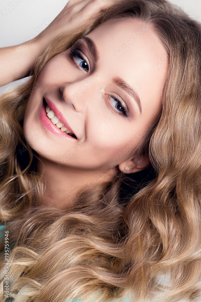 Model blonde with curls and evening make-up. Portrait of a young girl Model blonde with curls and evening make-up. Portrait of a young girl