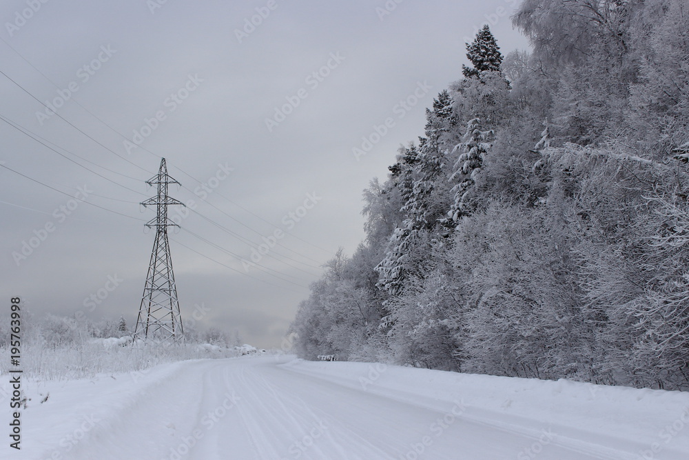 Dismal winter landscape heavy snowy and frozen power lines, mountain road and dark forest . Fabulously snowy mountain road in Siberia Dismal winter landscape heavy snowy and frozen power lines, mountain road and dark forest . Fabulously snowy mountain road in Siberia