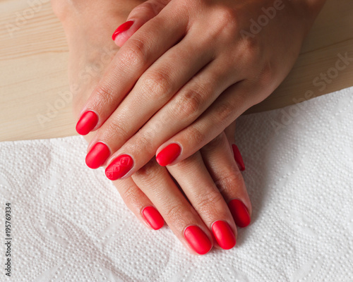 Beautiful female finger nails with red nail closeup on petals. Perfect manicure