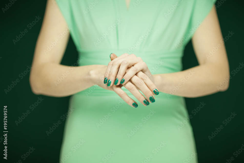 beautiful woman in green dress showing her hands with perfect green nail polish