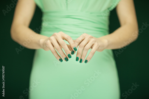 beautiful woman in green dress showing her hands with perfect green nail polish