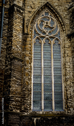 An arched window on Sint-Jacobskerk Monumental church featuring 12th-century Romanesque towers & a 13th-century Gothic central spire in Gent, Belgium,