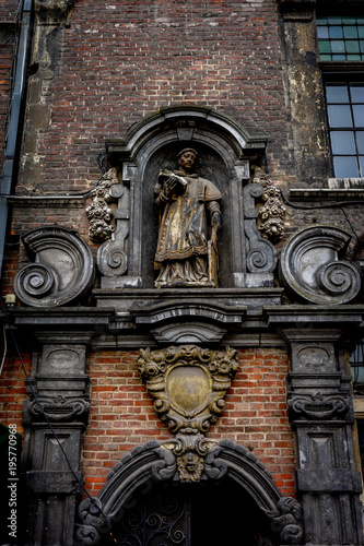 Statue of a person holding a book atop an arch in ghent, Belgium, Europe