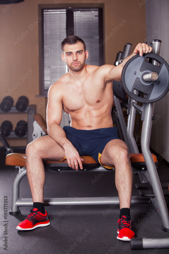 Fototapeta premium Brutal athletic man pumping up muscles on bench press