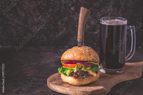 Homemade hamburger and beer on dark background with copy space