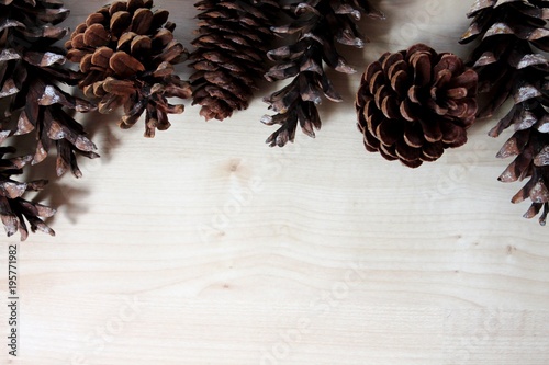 Pine cones top border on light wood background. Copy space.