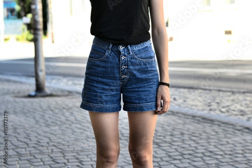 Młoda dziewczyna w dżinsowych spodenkach na ulicy.
