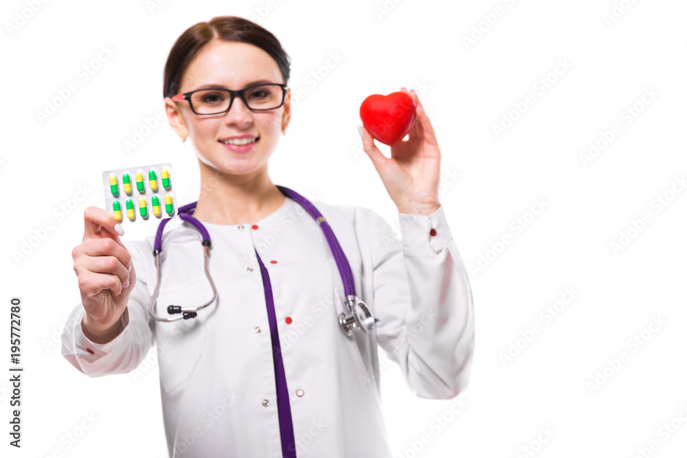 Young beautiful female doctor holding heart and pills in her hands isolated on white background Young beautiful female doctor holding heart and pills in her hands isolated on white background