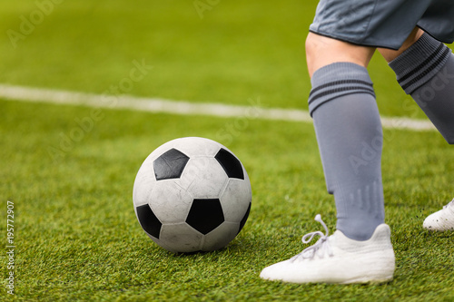 Football detail. Kicking the soccer ball. Football player feet and classic soccer ball on grass pitch. © matimix