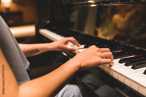 Asian woman hand playing keyboard of a piano in romantic atmosphere. Music instrument, solo pianist, song composer, hobby, practice study, or wedding event concept photo