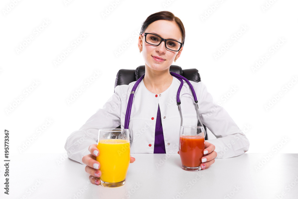 Female nutritionist sitting in her working place showing and offering glass of tomato and orange fresh juice on white background