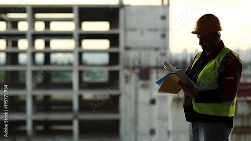 Master-builder with documentation on project site. Worker makes notes in his business papers. Building inspector writes in his documentation