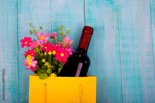 bottle of wine and flowers in the package on wooden background, space for text