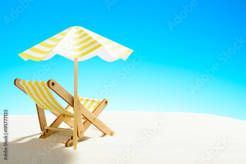 Fototapeta Naklejka Na Ścianę i Meble -  A chaise longue under an umbrella on the sandy beach, sky with copy space