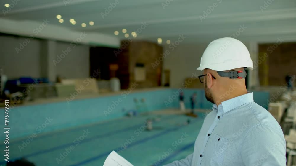 David Pool Engineer engineer looking at building plans in construction site. on the ...