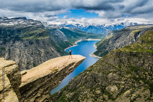 Amazing nature view with Trolltunga and a girl standing  on it. Location: Scandinavian Mountains, Norway, Stavanger. Artistic picture. Beauty world. The feeling of complete freedom