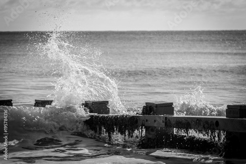 wave crashing against groyne in bay