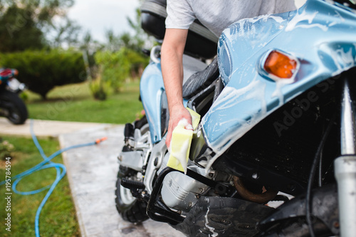 A man cleaning motorcycle with sponge, motorcycle detailing (or valeting) concept. Selective focus. 
