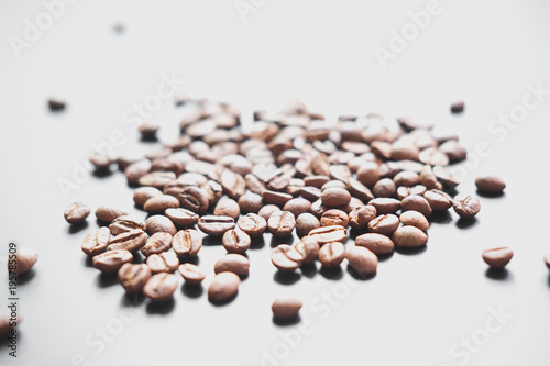 The grains of roasted coffee are scattered on a black matte surface