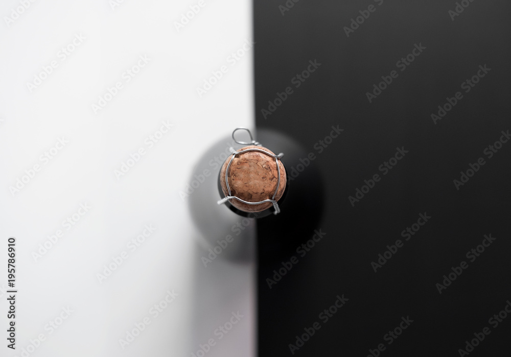a bottle of champagne with a closed stopper view from the top on a black - white background concept