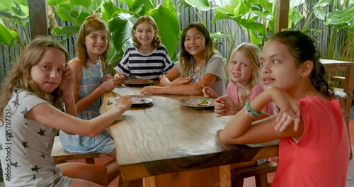 Group of multi ethnic young girls sitting at a table giving the thumbs up photo